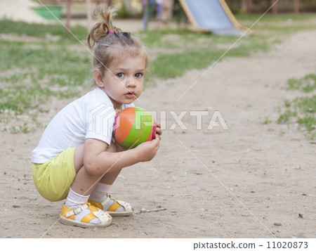 Little girl sitting on his haunches with a ball Playground Little girl sitting on his haunches with a ball Playground 11020873