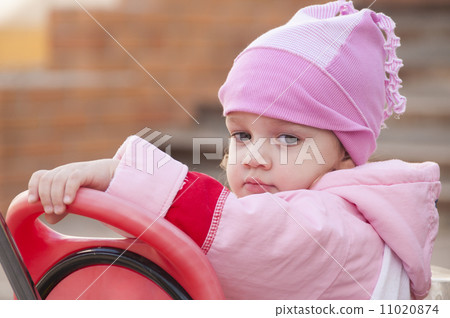 Two-year-old girl thoughtfully looks sitting on a bike Two-year-old girl thoughtfully looks sitting on a bike 11020874