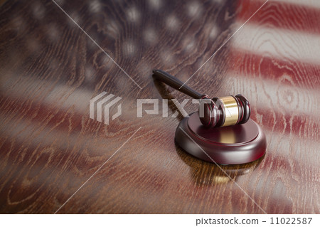 Wooden Gavel Resting on Flag Reflecting Table 11022587