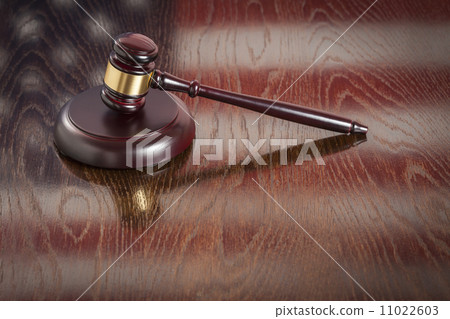 Wooden Gavel Resting on Flag Reflecting Table 11022603