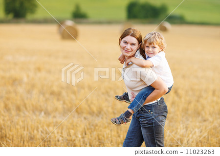 Young mother and her little son having fun on yellow hay field 11023263