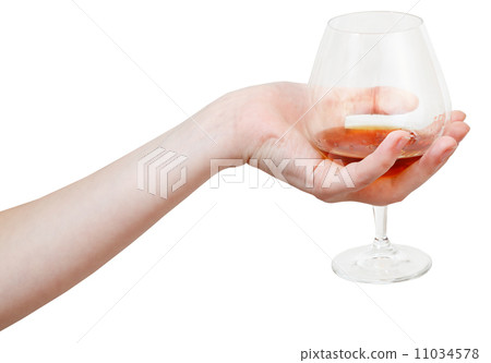 hand holds glass goblet with cognac isolated 11034578