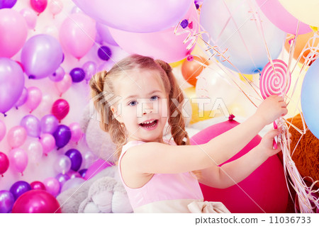 Merry little girl posing with bunch of balloons 11036733