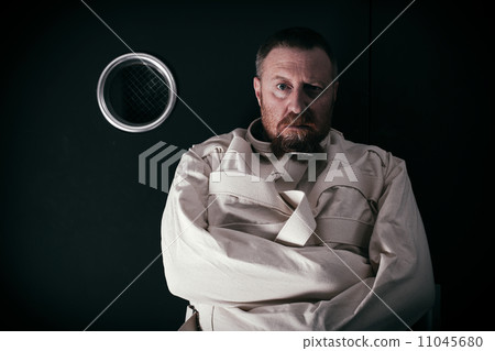 Insane man in a cell wearing a straitjacket Insane man in a cell wearing a straitjacket 11045680