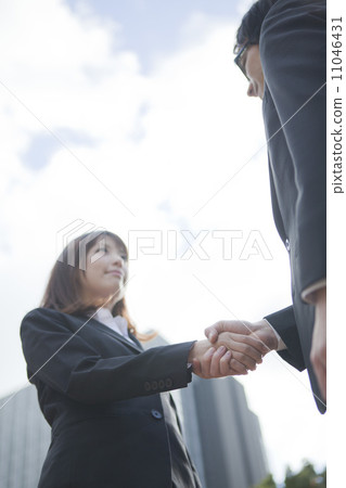 Business woman and businessman shaking hands in front of the building Business woman and businessman shaking hands in front of the building 11046431