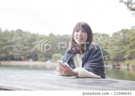 A woman wearing a knit sweater to touch her with a table at the park 11046641