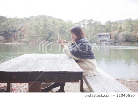 A woman wearing a knit sweater to touch her with a table at the park 11046650