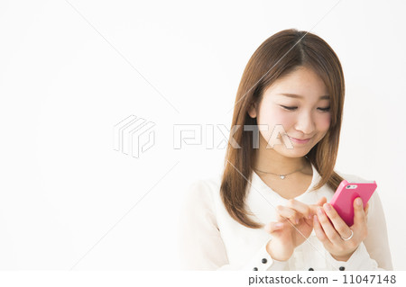 A young woman operating a smartphone 11047148