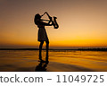 Saxophonist playing on saxophone against the background of sunset 11049725