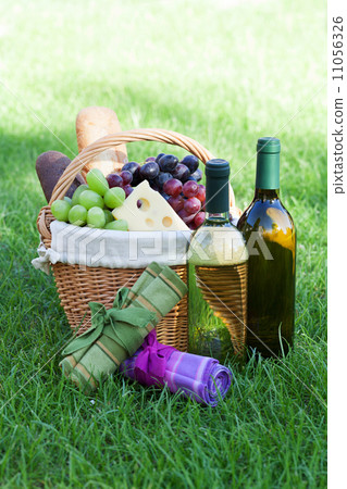 Outdoor picnic basket with wine on lawn Outdoor picnic basket with wine on lawn 11056326