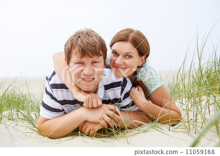 Young happy couple in love having fun on sand dunes of the beach Young happy couple in love having fun on sand dunes of the beach 11059168
