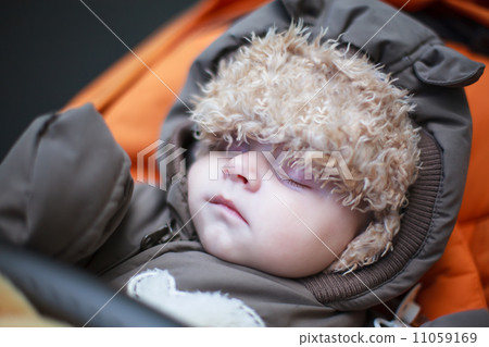 Adorable baby boy in winter clothes sleeping in stroller Adorable baby boy in winter clothes sleeping in stroller 11059169