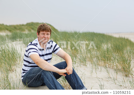 Young happy man relaxing on sand dunes of the beach of St.Peter 11059231