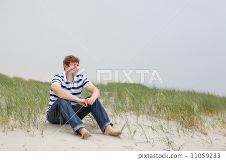 Young happy man relaxing on sand dunes of the beach of St.Peter 11059233