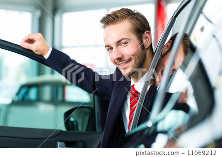 Young man or auto dealer in car dealership Young man or auto dealer in car dealership 11069212