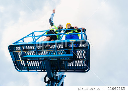 Construction workers on site in hydraulic lifting ramp 11069285