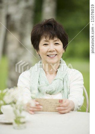 Senior woman smiling with a postcard 11076019