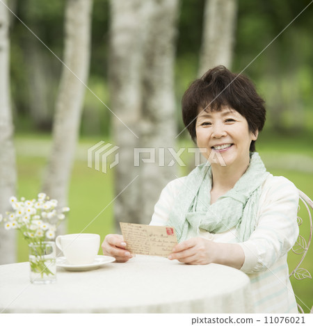 Senior woman smiling with a postcard 11076021