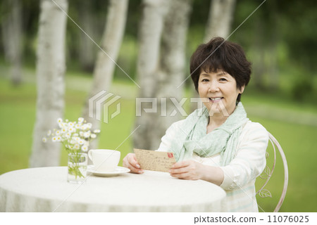 Senior woman smiling with a postcard 11076025