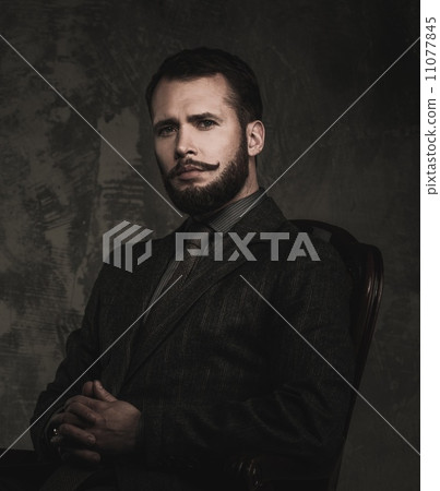 Handsome well-dressed with stick sitting in leather chair 11077845