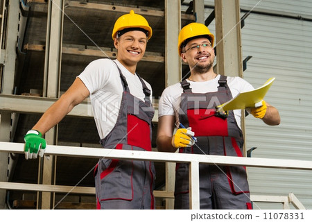 Two positive workers in safety hats on a factory Two positive workers in safety hats on a factory 11078331