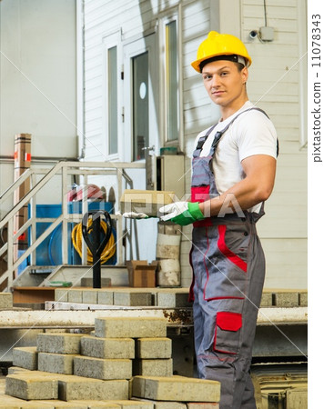 Young worker near conveyor belt with paving stone on a factory Young worker near conveyor belt with paving stone on a factory 11078343