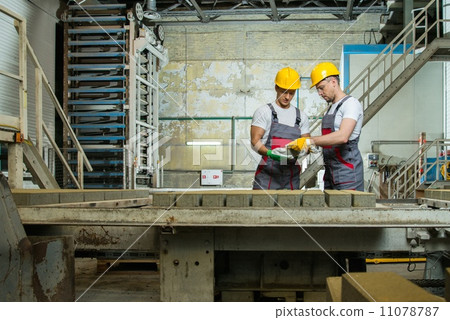 Worker and foreman in a safety hats performing quality check on a factory Worker and foreman in a safety hats performing quality check on a factory 11078787