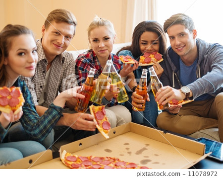 Group of young multi ethnic friends with pizza and bottles of drink celebrating in home interior Group of young multi ethnic friends with pizza and bottles of drink celebrating in home interior 11078972