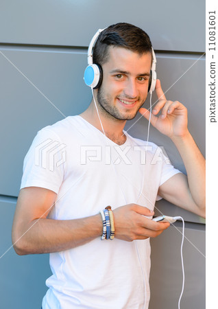 Smiling student boy with headphones against wall Smiling student boy with headphones against wall 11081601
