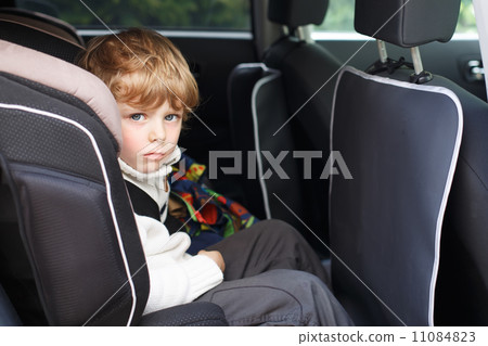 Portrait of little boy sitting in safety car seat 11084823