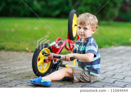 Happy funny toddler boy of three years repairing his first bike 11084844