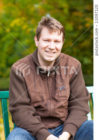 young man in the autumn park sitting on bench young man in the autumn park sitting on bench 11097320