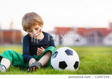 Blond boy of 4 playing soccer with football on football field 11097348