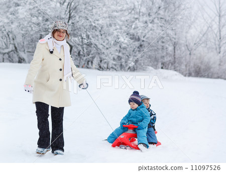 Two little siblings and their mother having fun on sledge on win Two little siblings and their mother having fun on sledge on win 11097526
