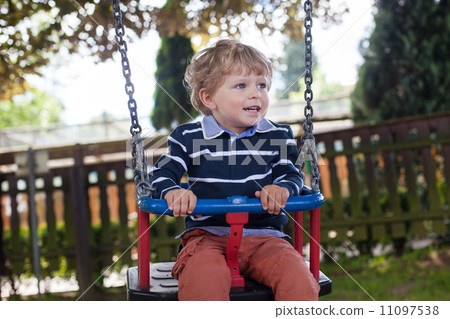 Beautiful toddler boy having fun on swing Beautiful toddler boy having fun on swing 11097538