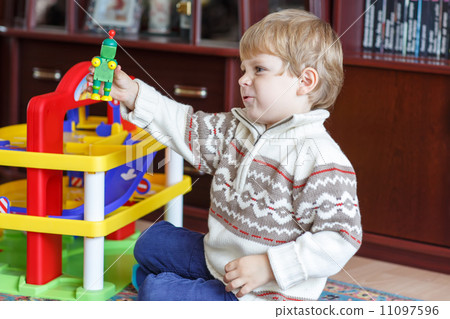 Little blond boy of three years playing with toys at home 11097596
