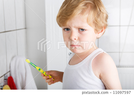 Lovely toddler with blue eyes and blond hair brushing his teeth 11097597