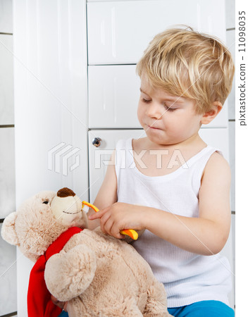 Little boy playing with teddy bear toy and brushing teeth. 11098035