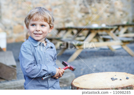 Little blond boy playing with hammer outdoors. Little blond boy playing with hammer outdoors. 11098285