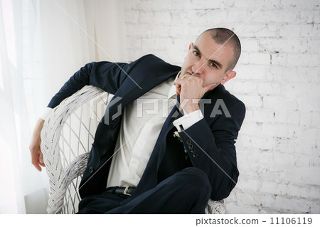Confident smiling young businessman sitting on a white chair 11106119