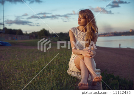 Young beauty smiling relaxing girl woman sitting near river or lake in nature outdoors portrait. Sof Young beauty smiling relaxing girl woman sitting near river or lake in nature outdoors portrait. Sof 11112485