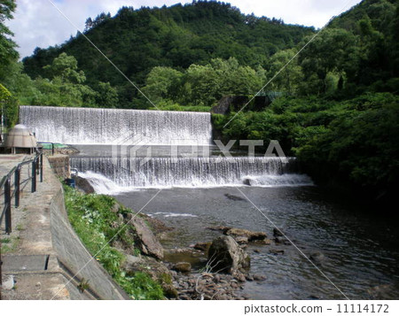 一個河流夏天的涼爽景色，水流分兩個階段，從大壩作為瀑布的巨大力量 11114172