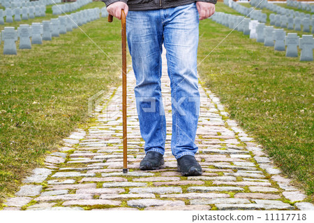 Man with walking stick in cemetery 11117718