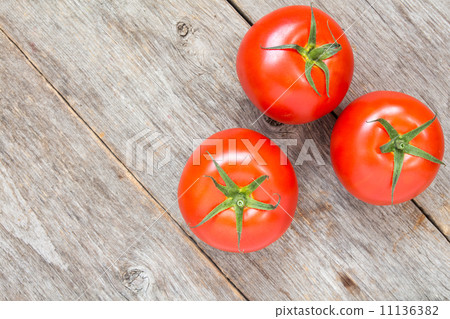 Three tomatoes on wooden background 11136382