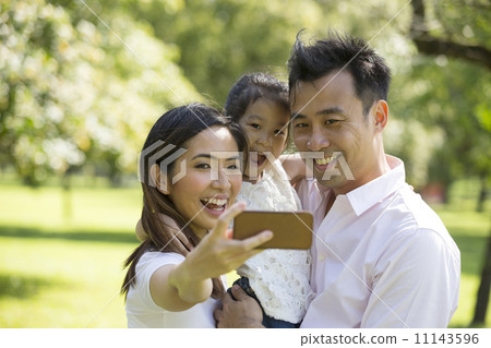 Happy Asian family taking selfies with there smartphone in the p Happy Asian family taking selfies with there smartphone in the p 11143596