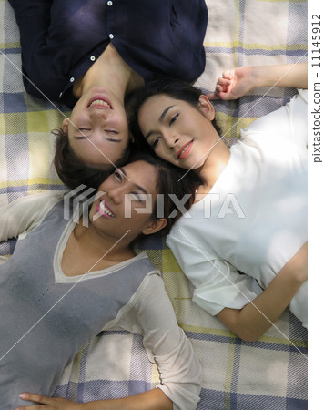 girls relax on picnic mat in park girls relax on picnic mat in park 11145912