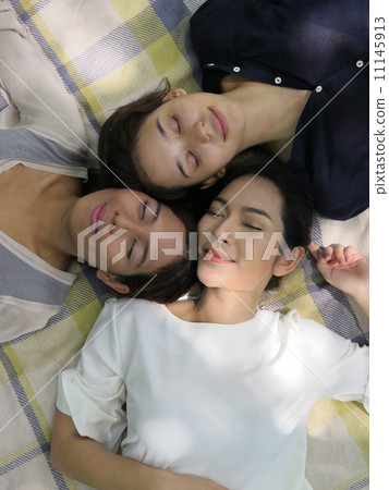 girls relax on picnic mat in park 11145913