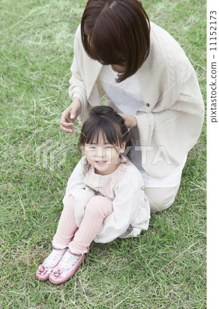 Mother and child tying hair on the lawn Mother and child tying hair on the lawn 11152173