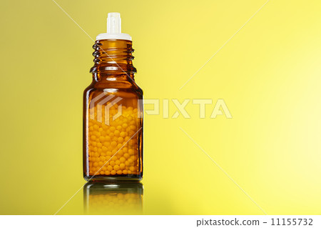 single bottle with homeopathy globules with yellow background single bottle with homeopathy globules with yellow background 11155732