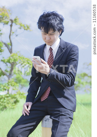 A businessman looking at a smartphone 11160538
